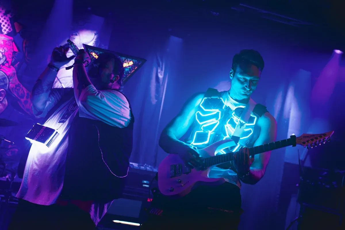 Saenger und Gitarrist mit leuchtender LED-Weste im blauen Nebel