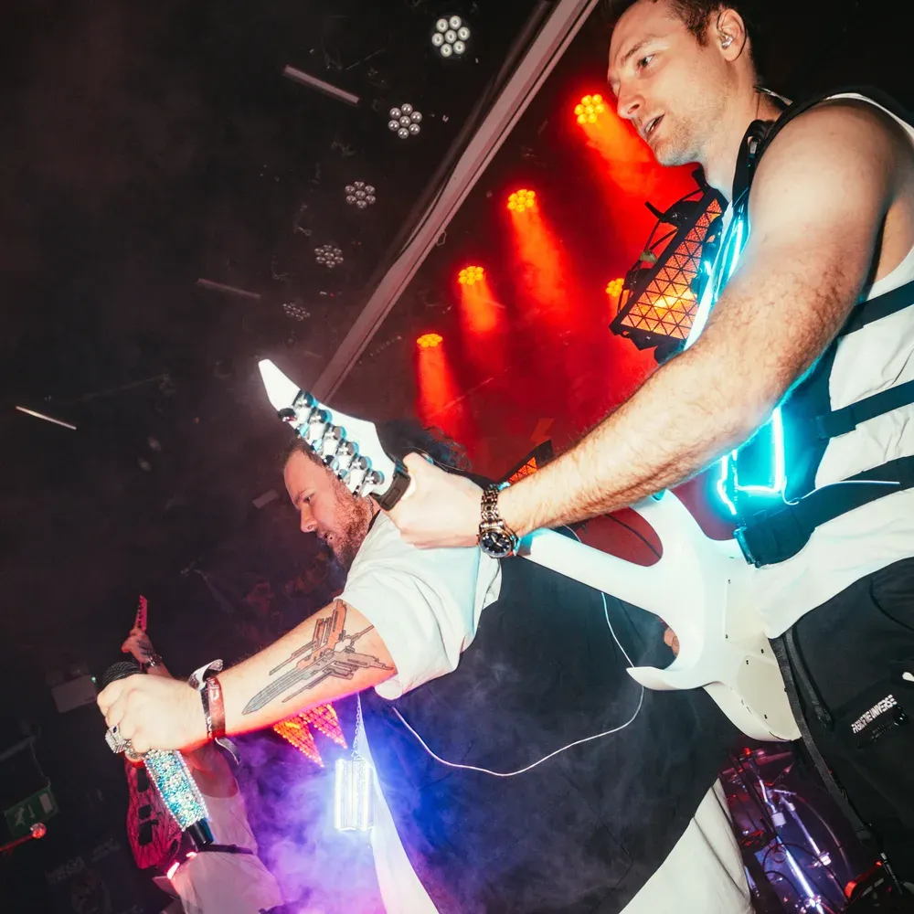 Saenger und Gitarrist Schulter an Schulter unter lila Licht